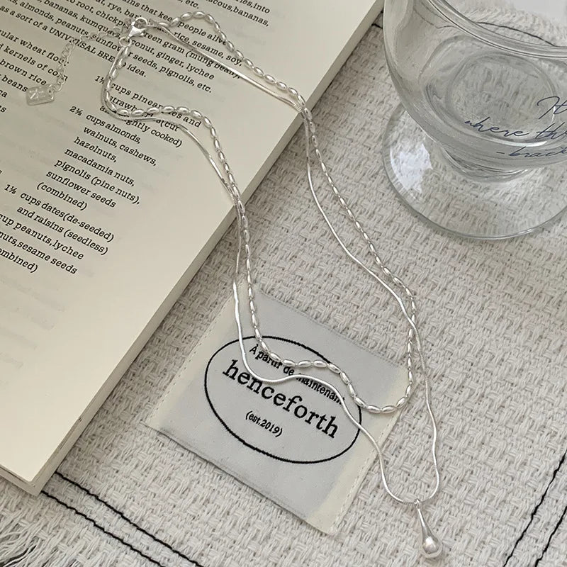 Halsband med dubbla kedjor och en droppformad berlock