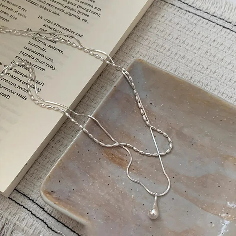 Halsband med dubbla kedjor och en droppformad berlock