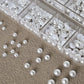 Låda med små pearls eller strass stenar med verktyg
